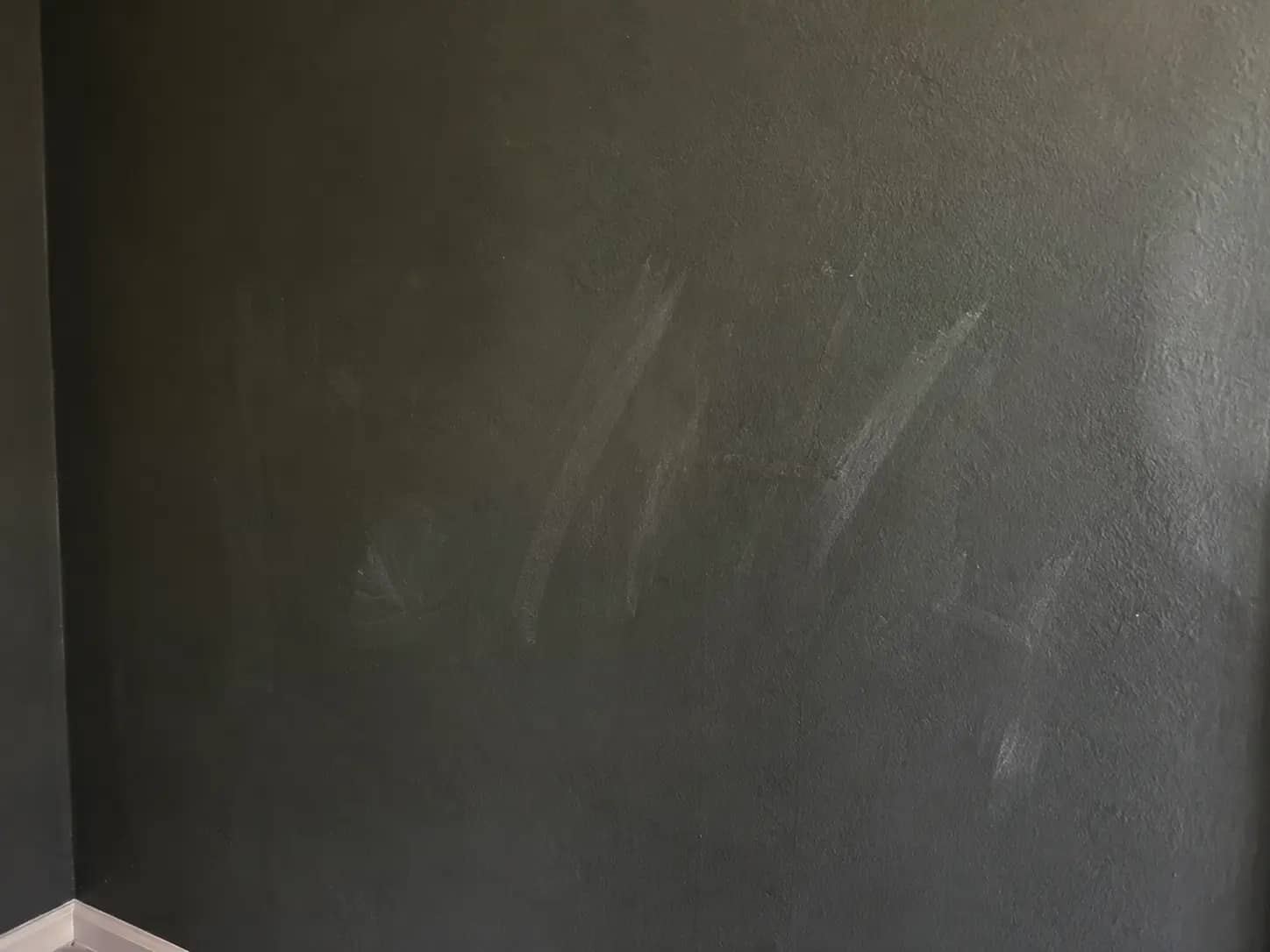 Detailaufnahme heller Streifen auf einer matten anthrazitfarbenen Wand, Schreibeffekt nach Reibung