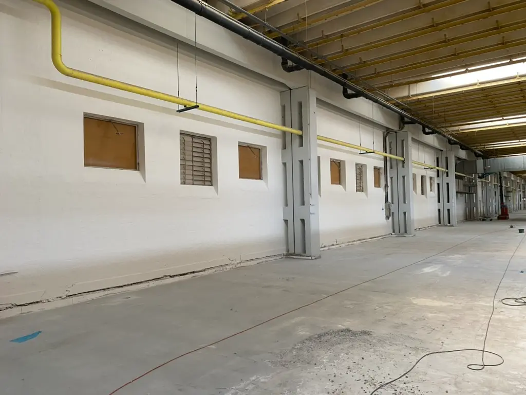 Modernes Einkaufszentrum mit dunkelroter Putzfassade und geschwungener Glasfront – gewerbliche Fassadengestaltung Magdeburg